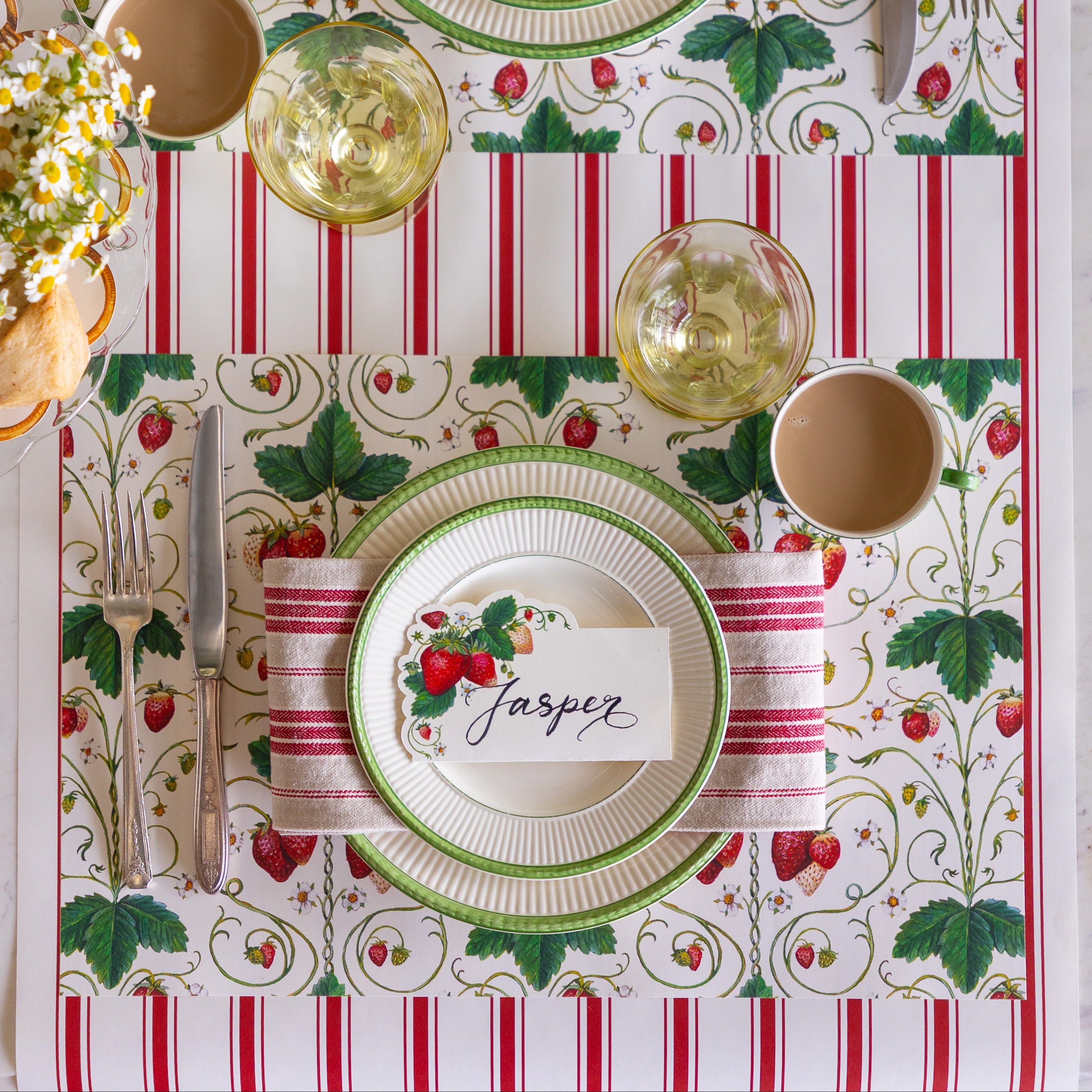 Table setting with the Strawberry Fields Placemat, green rimmed plates, red striped napkin, Strawberries Place Card and vintage cutlery on the Red Linen Stripe Runner.