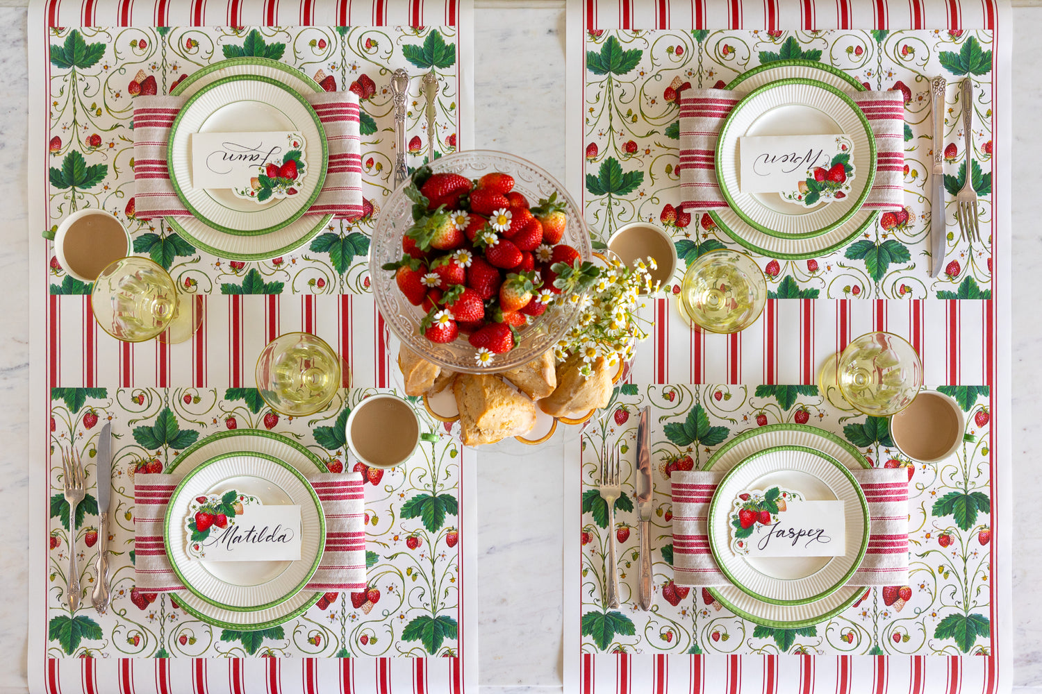 Table setting with strawbeerries, scones and flowers, the Strawberry Fields Placemat, green rimmed plates, red striped napkin, Strawberries Place Card and vintage cutlery on the Red Linen Stripe Runner.