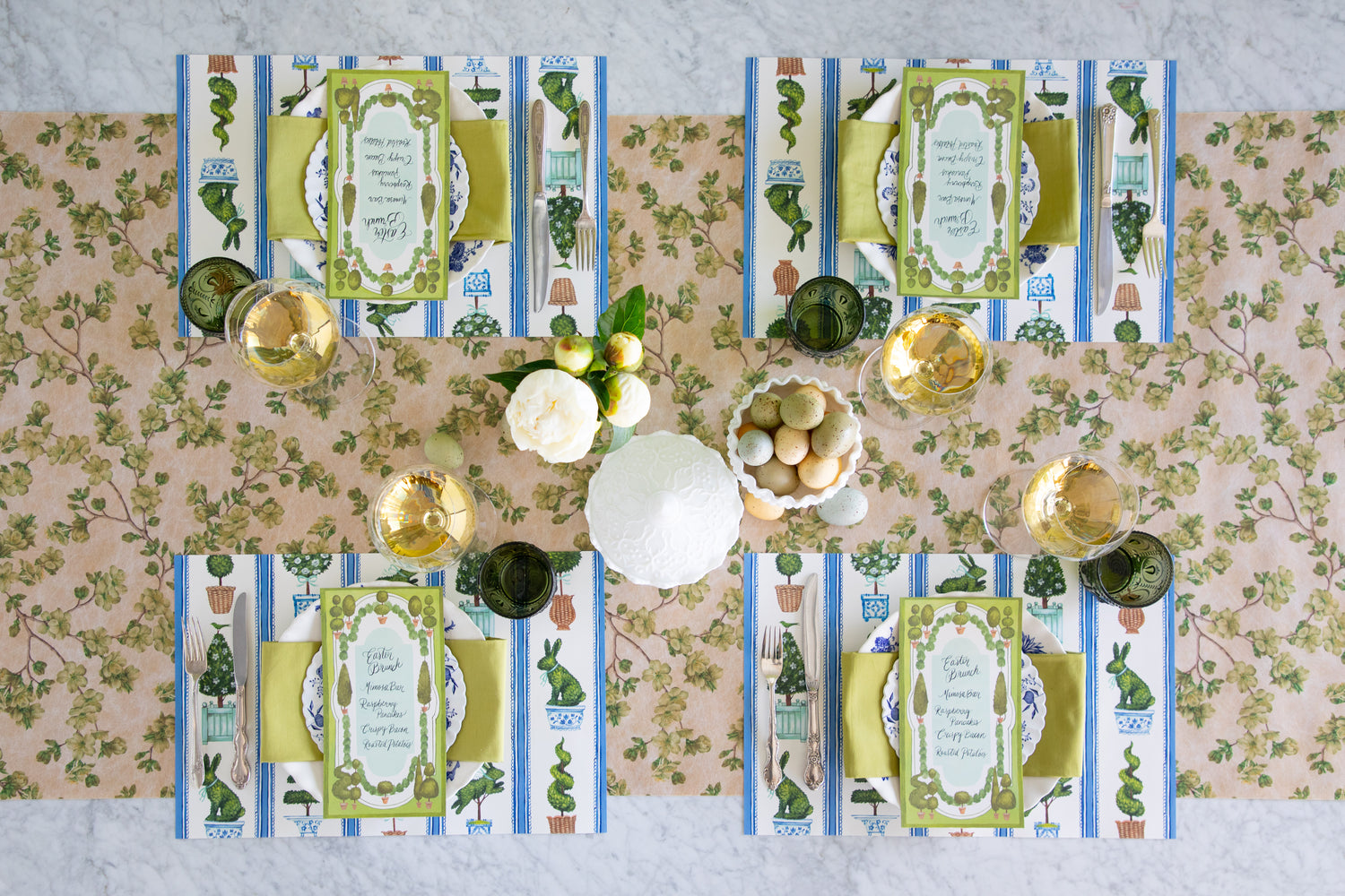 Easter table setting with eggs, flowers, Spring Topiary Placemats, Topiary Garden Table Cards, floral plates and greens napkin on the Green Cherry Blossom Runner.