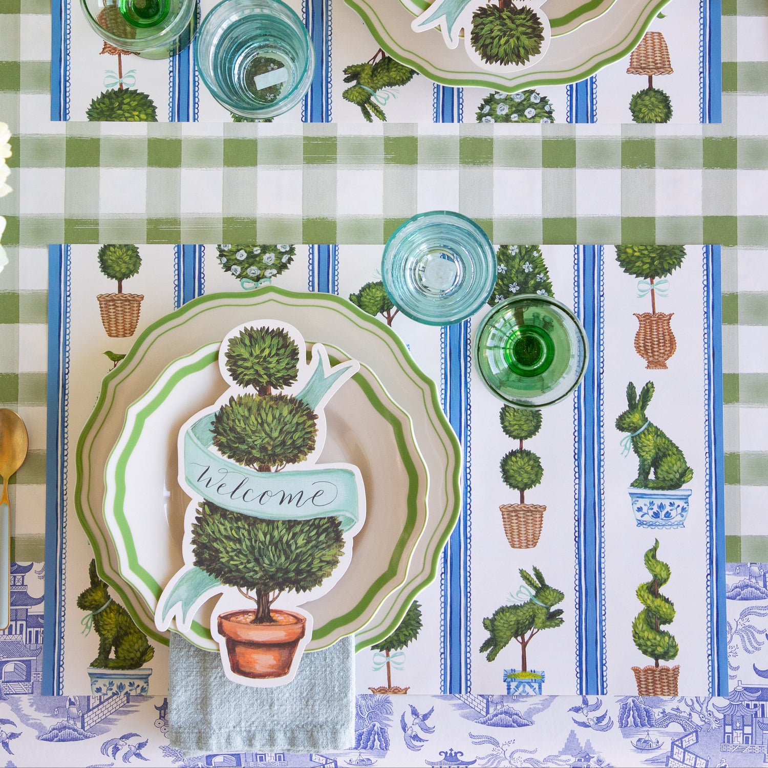 Place setting with the Spring Topiary Placemat, Topiary Table Accent, Green Icing on the Cake Plates, seafoam napkin and cutlery on the Moss Painted Check and Blue Regal Peacock Runners.