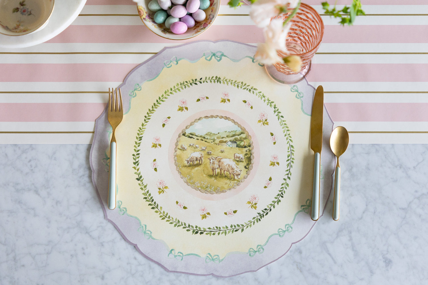 Die-cut Spring Meadow Placemat and seafoam and gold cutlery on an Easter table setting on the Pink &amp; Gold Awning Stripe Runner.