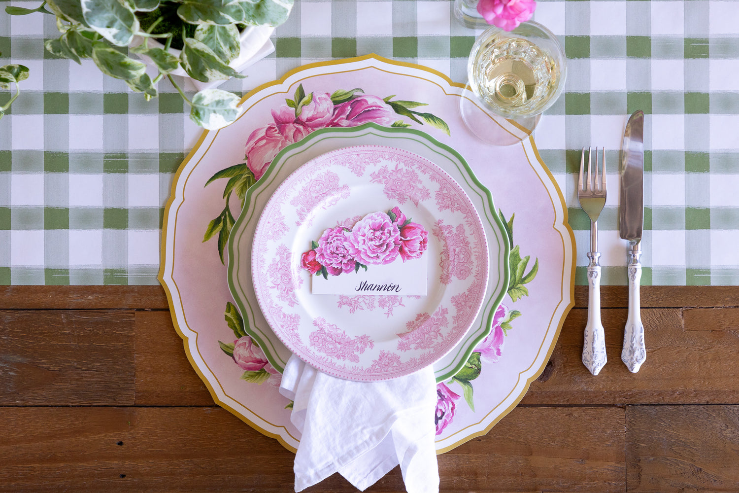An elegant place setting with the Die-cut Peony China Placemat, green rimmed and pink floral plates, white napkin and vintage cutlery on the Moss Painted Check Runner.