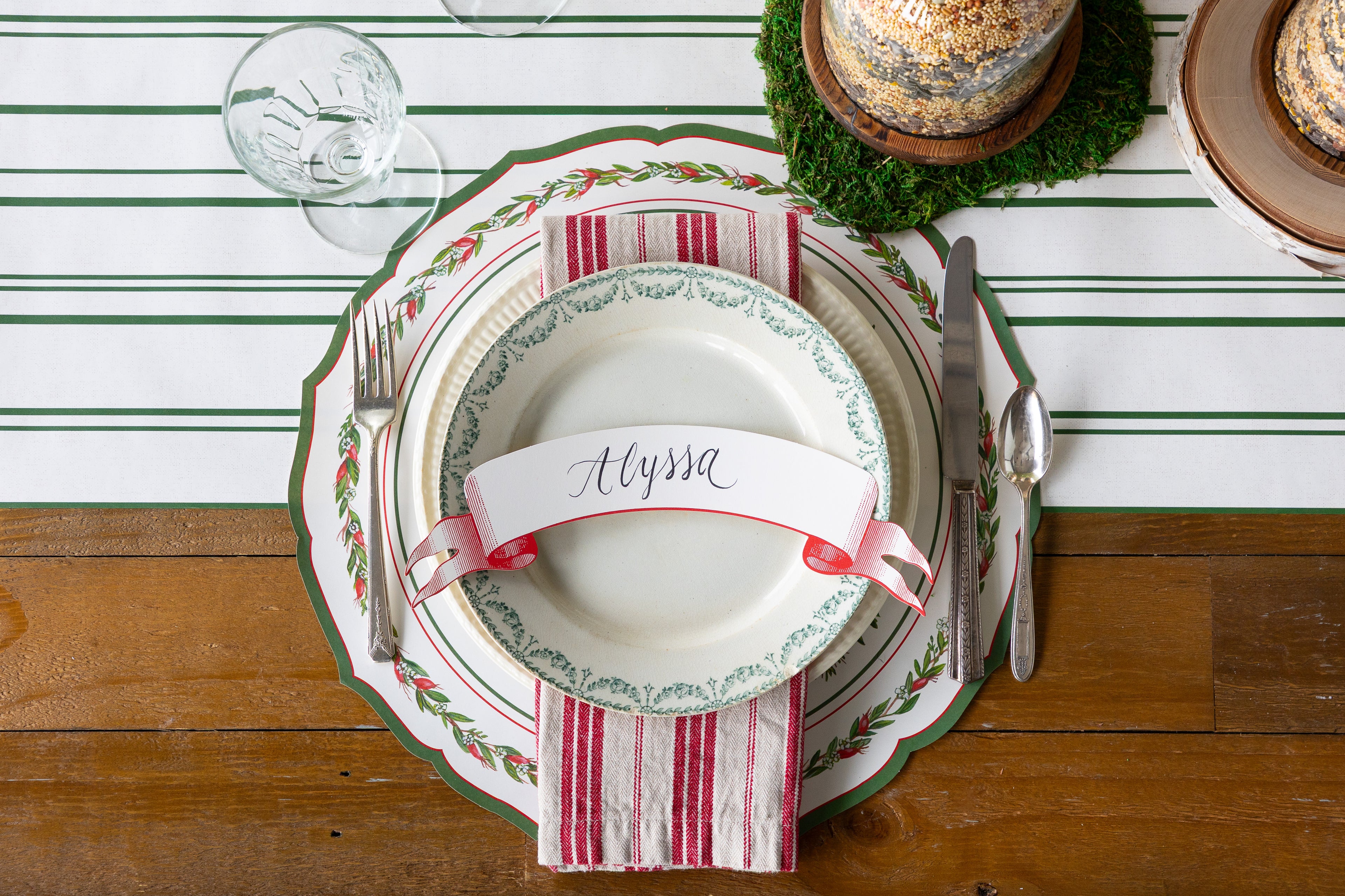 Christmas-themed table setting with place card on a striped table runner. 