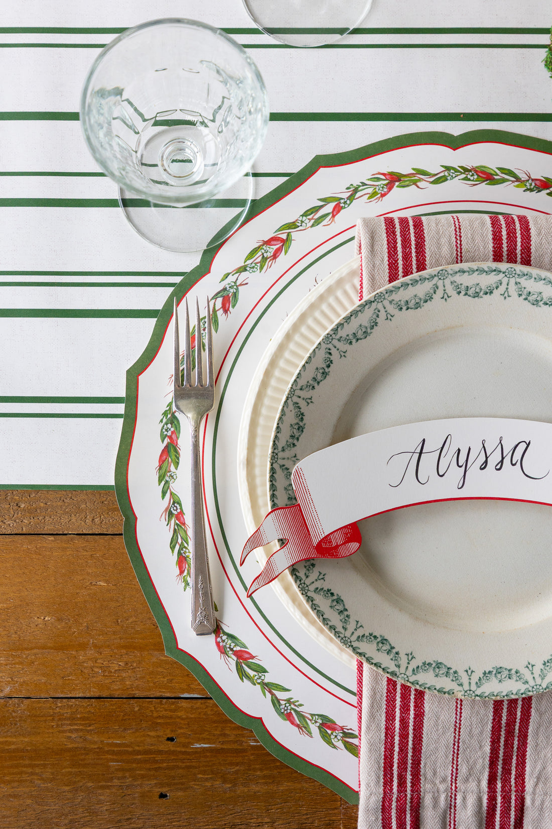 Christmas-themed place setting with a name card on a striped table runner.