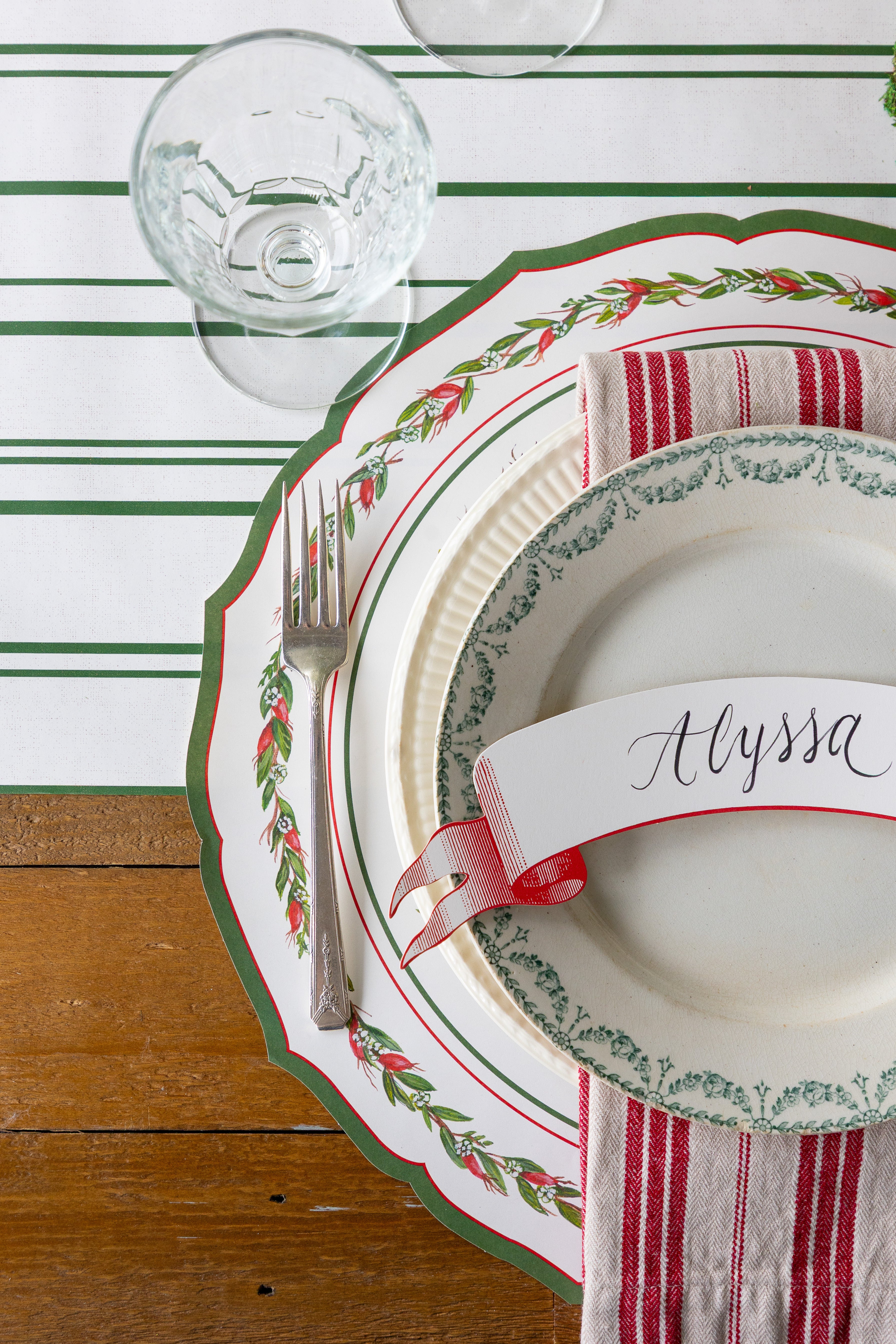 Christmas-themed place setting with a name card on a striped table runner.