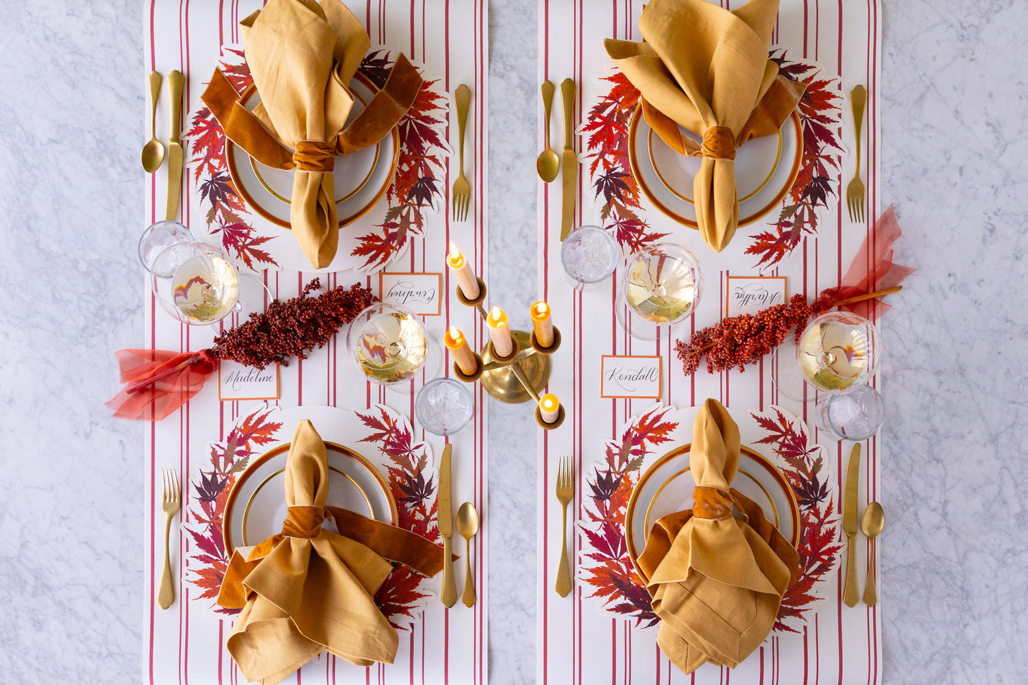 Decorative table setting with gold napkins, plates, and cutlery on a patterned tablecloth.