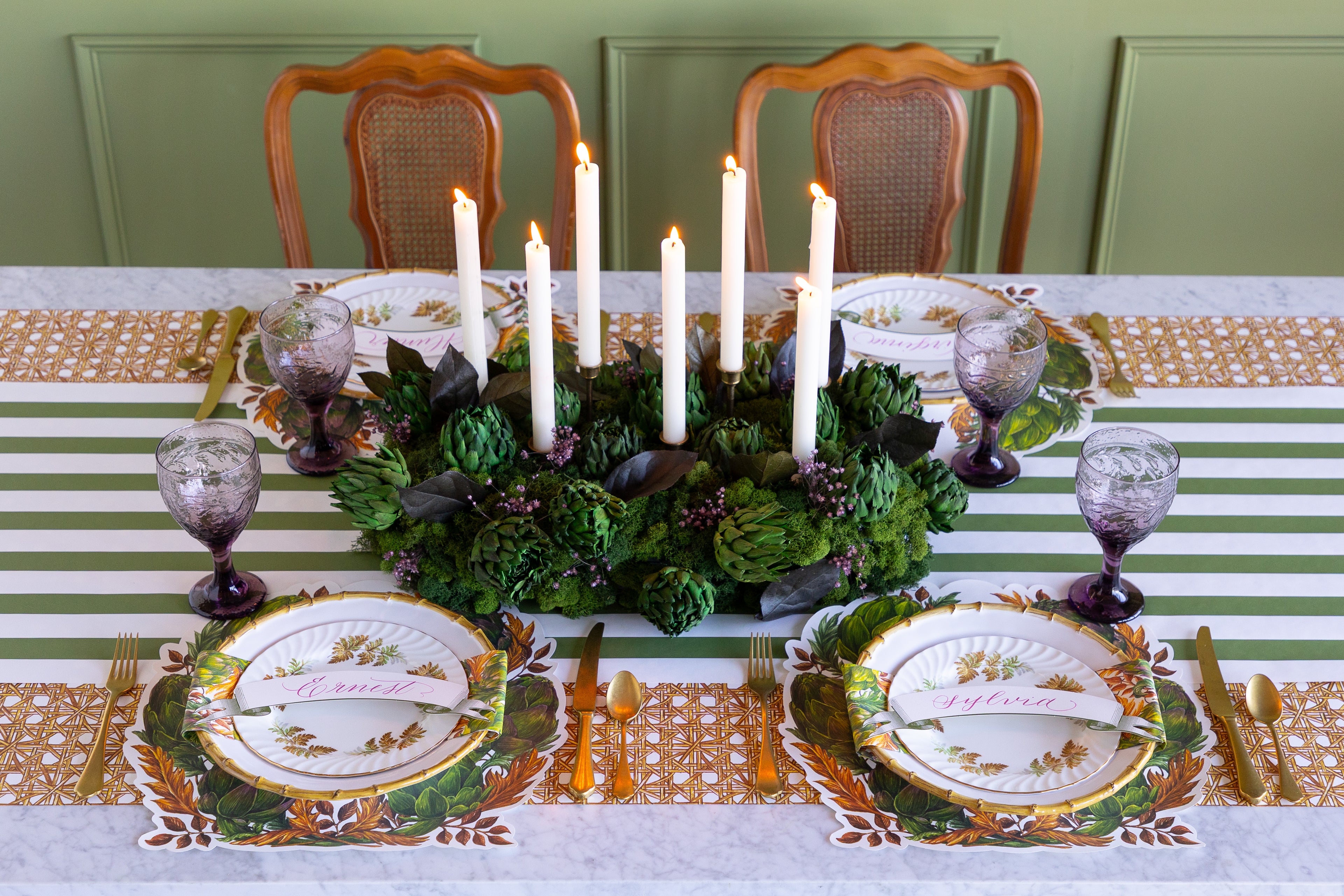 Decorative table setting with place cards, napkins, and a floral centerpiece on a patterned tablecloth.