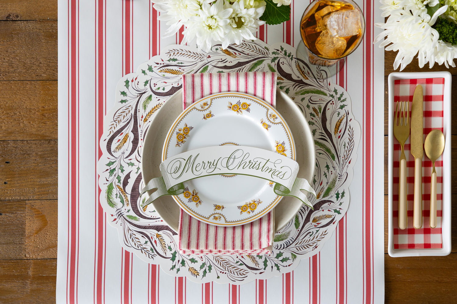 Placesetting with the Die-cut Merry Christmas Placemat on a red stripe table runner with vintage plates on it. 