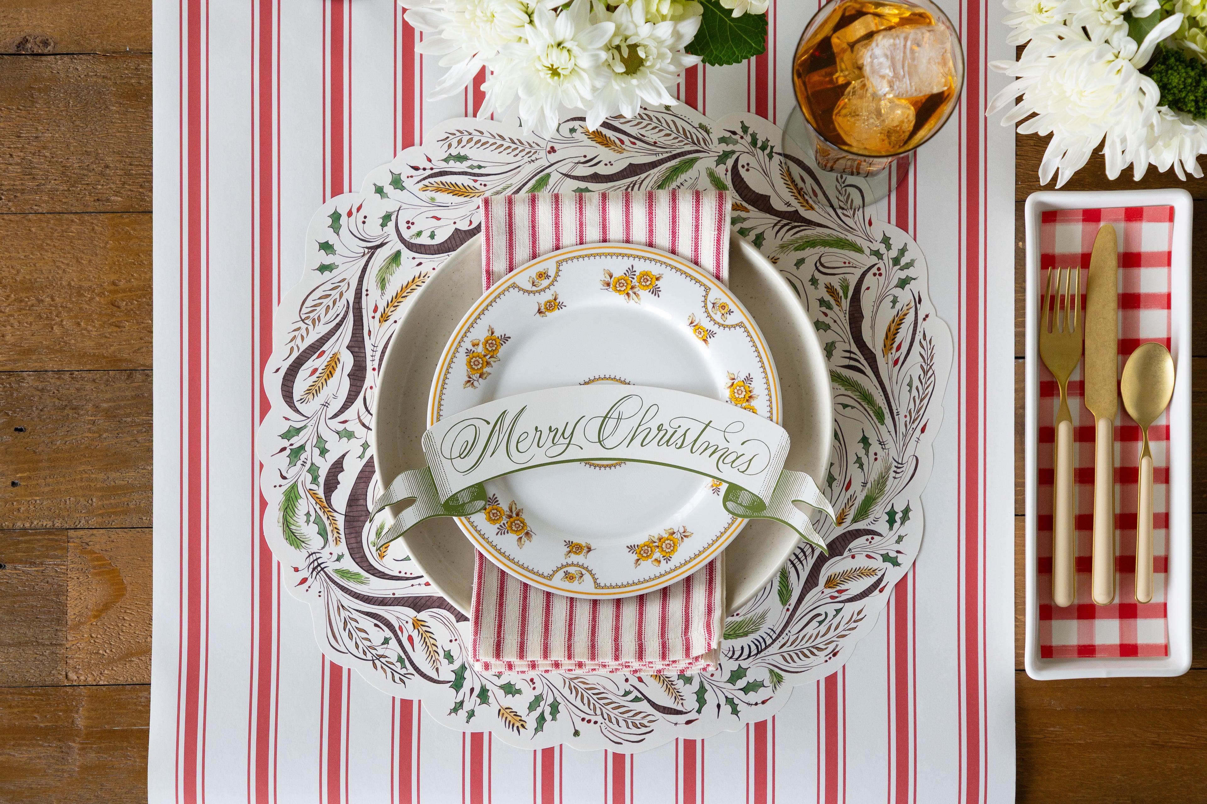 Placesetting with the Die-cut Merry Christmas Placemat on a red stripe table runner with vintage plates on it. 