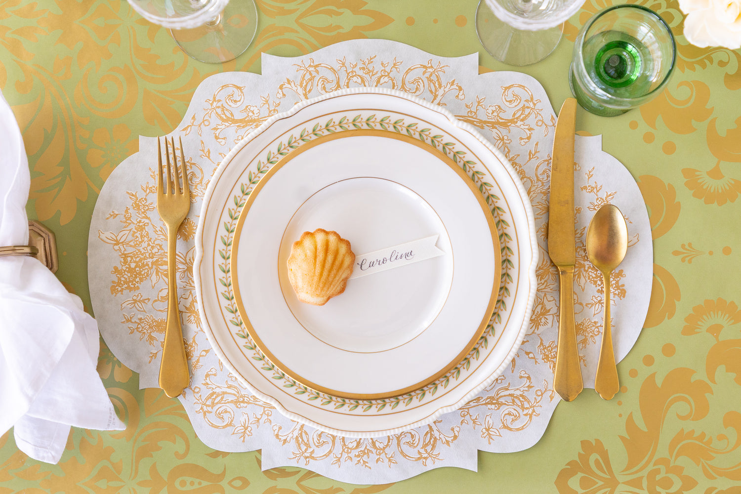 Elegant place setting with gold cutlery and a white plate on the Die-Cut Gilded Scroll Frame Placemat.