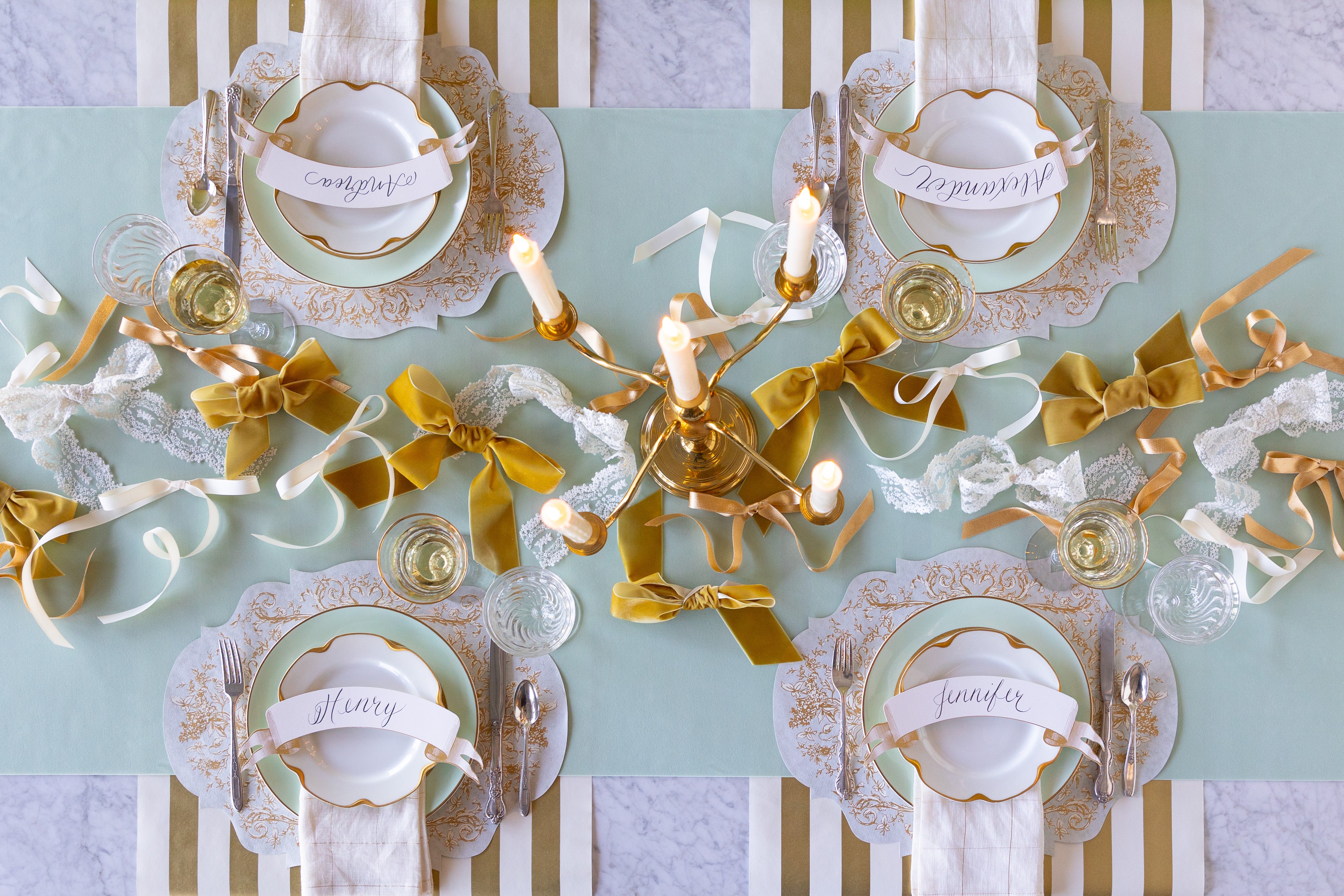 Elegant table setting with bows made of different fabrics strewn down the center of a table on a Seafoam Seafoam Flocked Runner. 