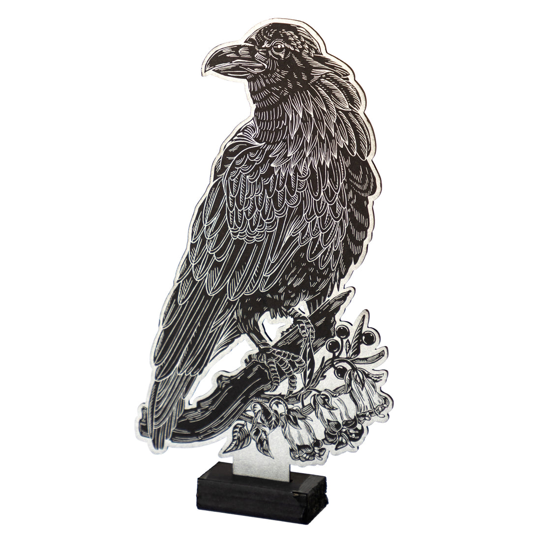 Raven Table Ornament is a black cutout of a raven perched on a branch with silver line-work, displayed upright on a small black stand.