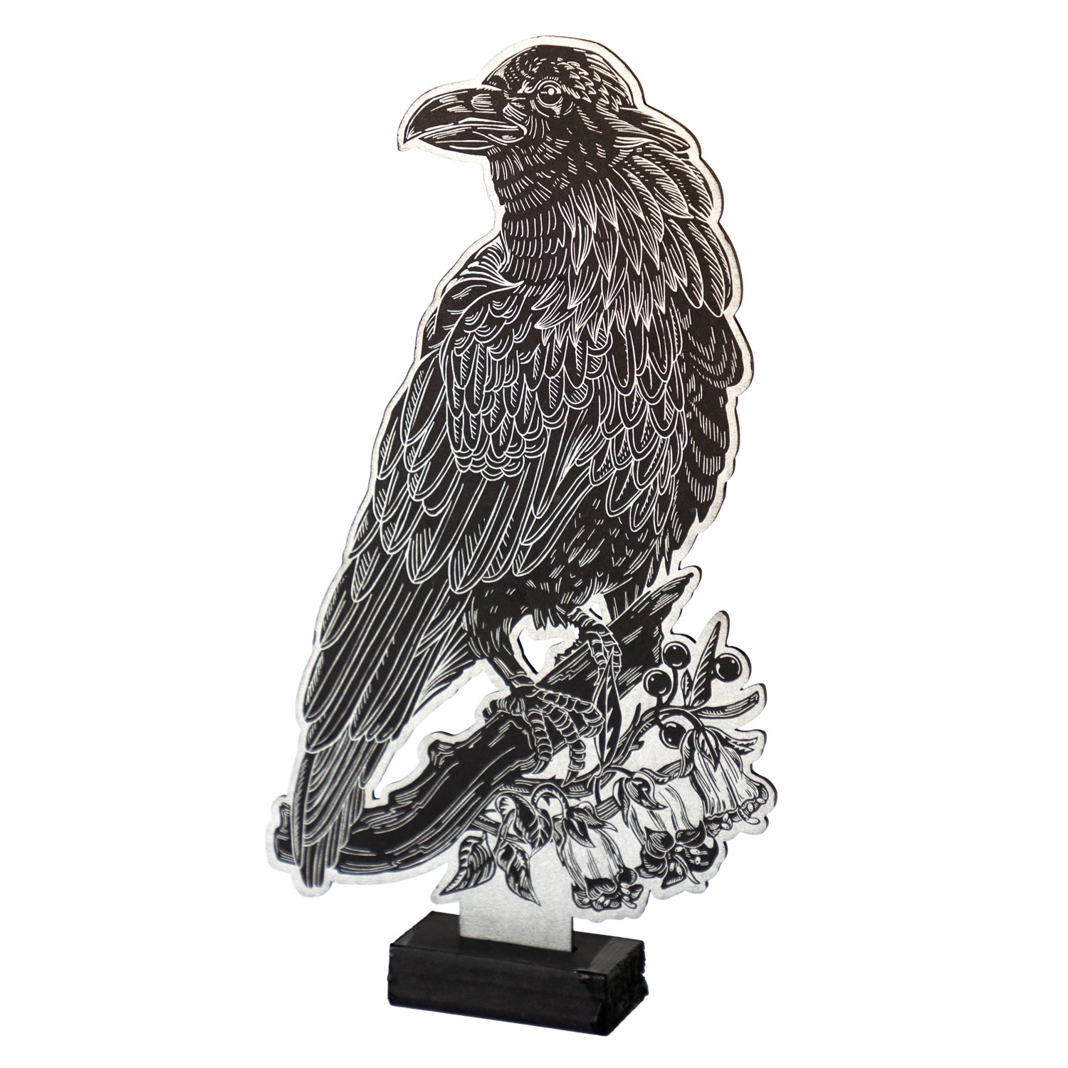 Raven Table Ornament is a black cutout of a raven perched on a branch with silver line-work, displayed upright on a small black stand.