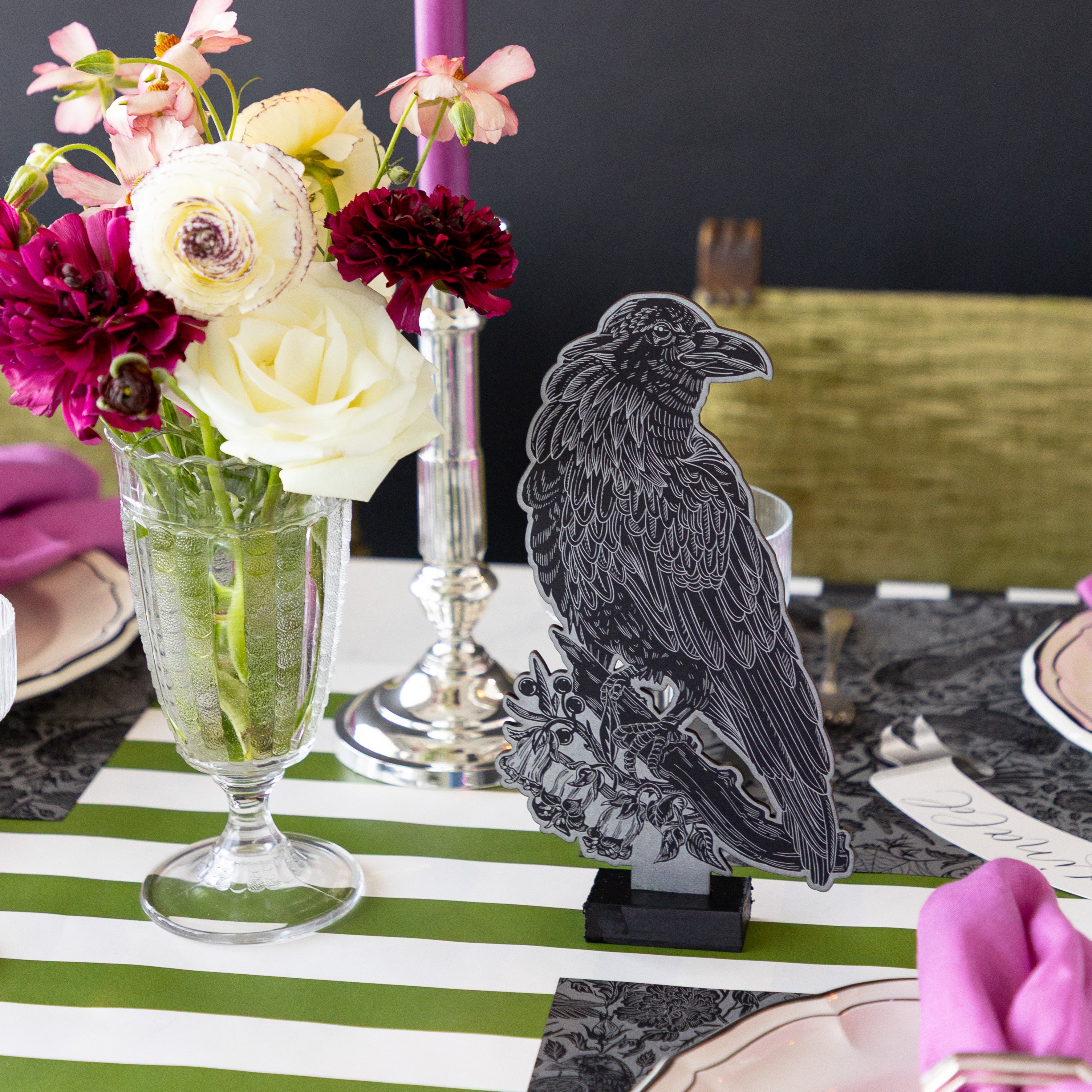 The Raven Table Ornament behind a place setting featuring the Raven Toile Placemat,  flowers and Moss Green Classic Stripe Placemat underneath.