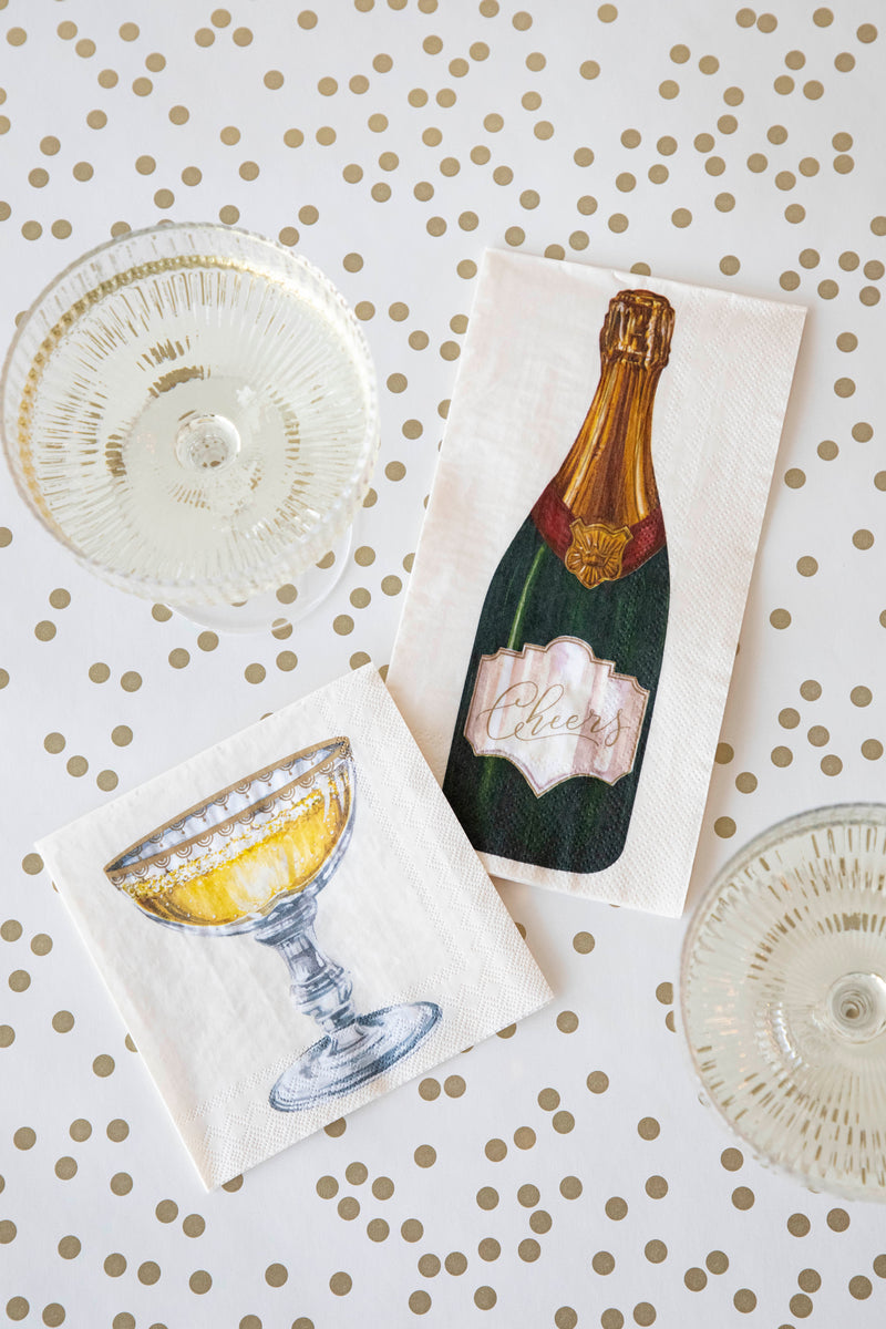A top-down view of a table with two glasses of champagne with a Champagne Coupe Guest and Cocktail Napkin.