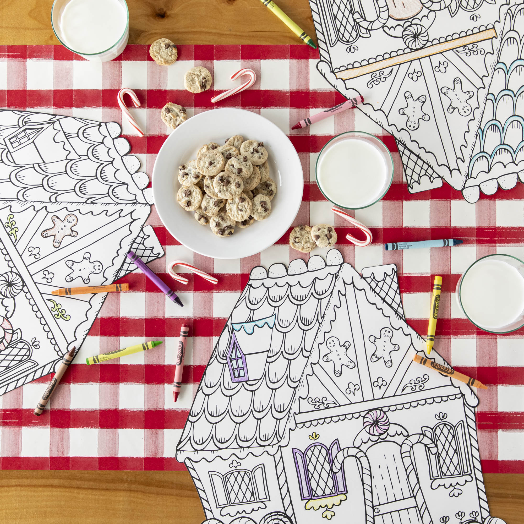 The Red Painted Check Runner under the Die-cut Coloring Gingerbread House, a plate of cookies, and crayons and candy canes scattered.