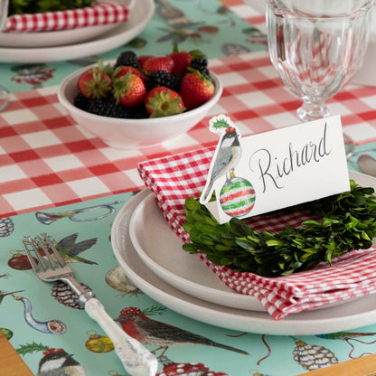 The Baubles and Birds Placemat on under a Christmas table setting, featuring the Christmas Chickadee Place Card.