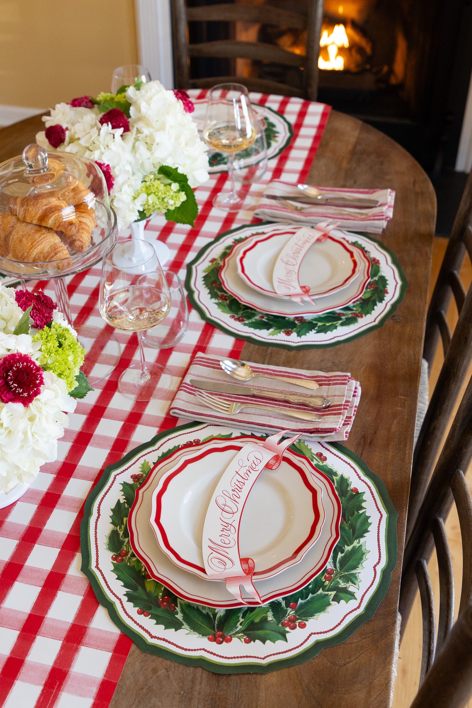 Decorative Christmas table setting with plates, napkins, and flowers on a checkered tablecloth.