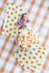 A top-down view of a Halloween treat table featuring a Candy Corn Guest Napkin and three Candy Corn Cocktail Napkins fanned out on the table. 