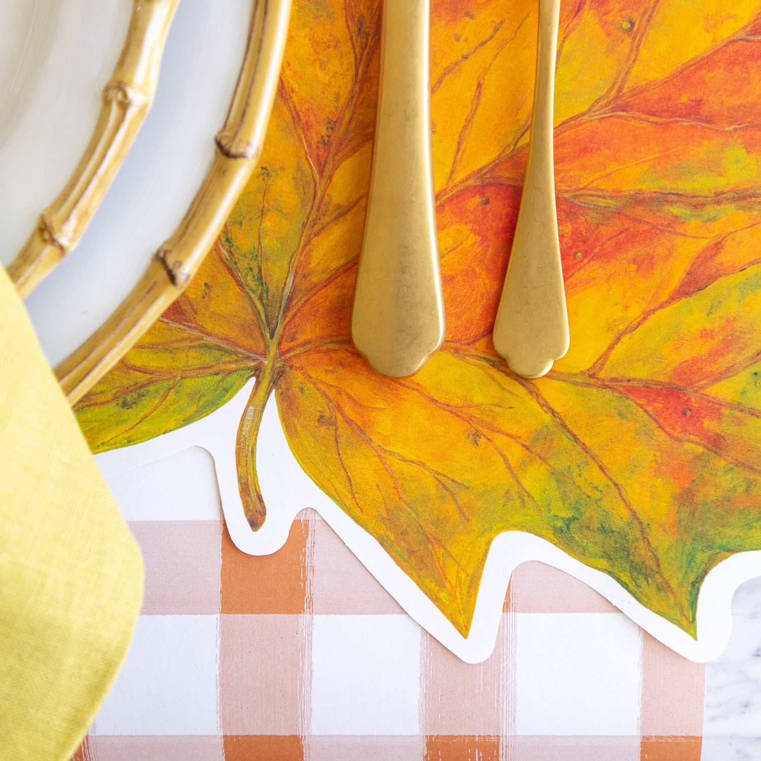 The Die-cut Fall Leaf Placemat under an elegant place setting and Orange Painted Check Runner underneath.