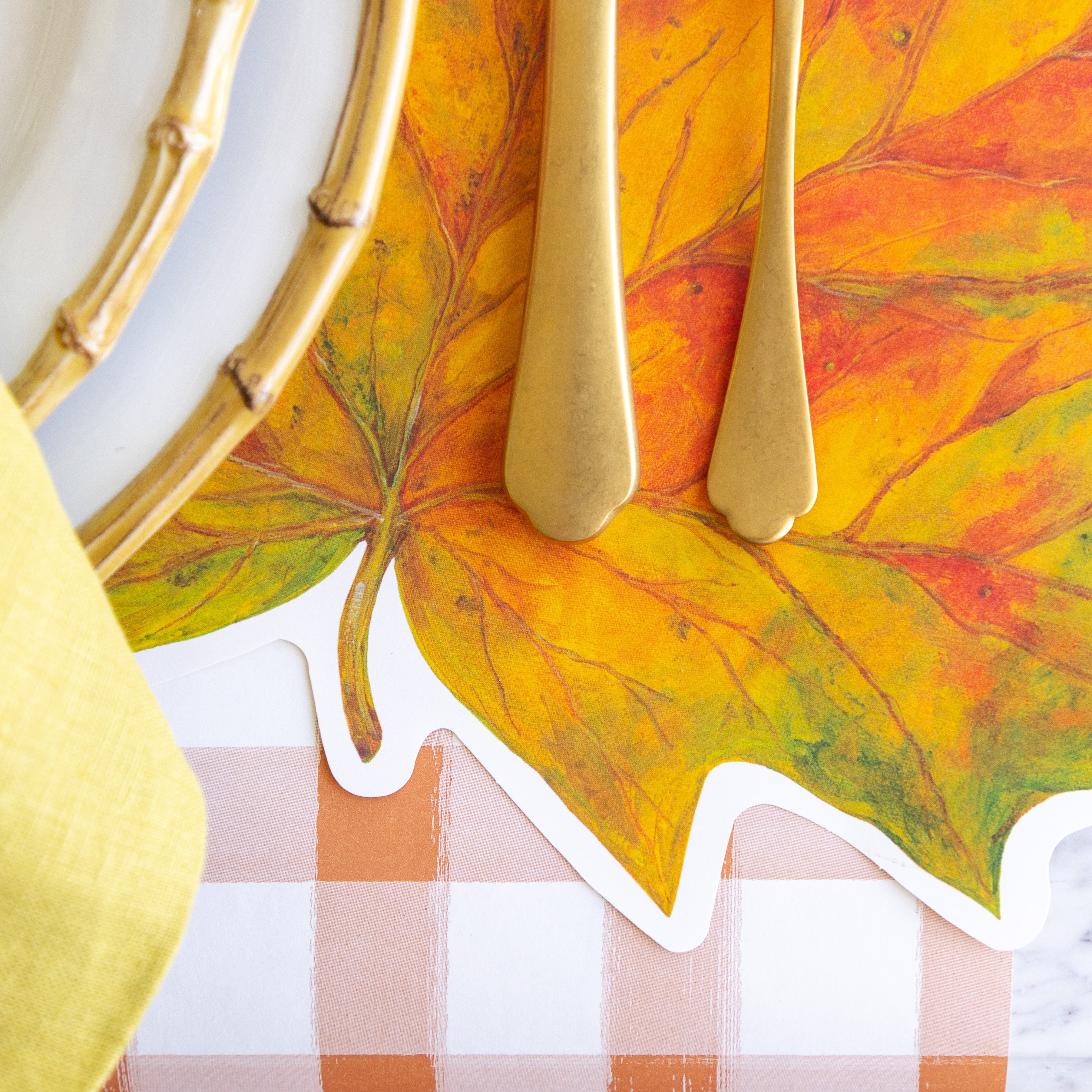 The Die-cut Fall Leaf Placemat under an elegant place setting and Orange Painted Check Runner underneath.