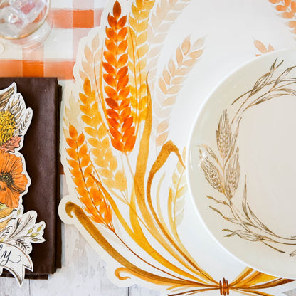 A table setting with a plate, napkin, and Hester &amp; Cook Die-cut Golden Harvest Placemat.