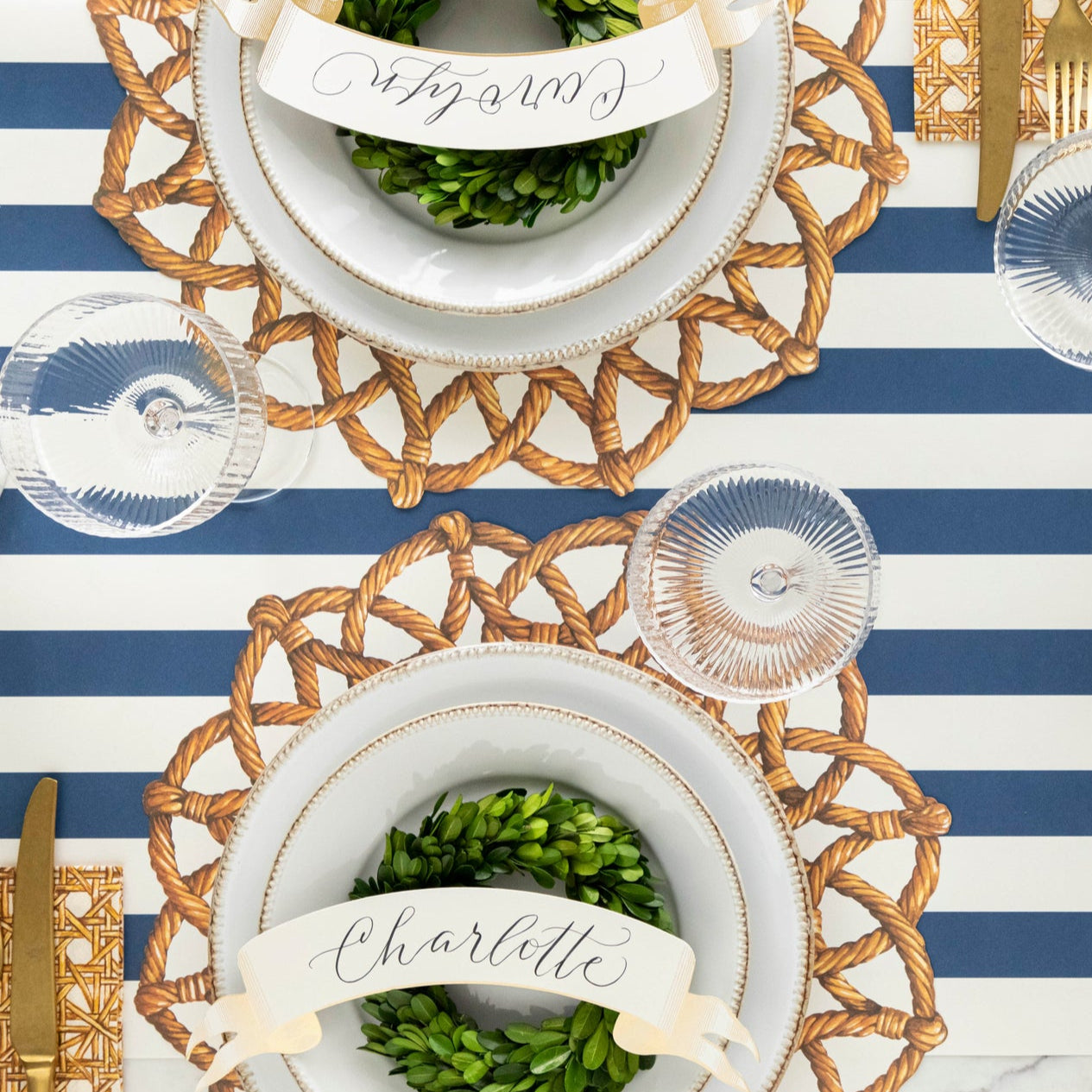 Elegant table setting featuring Die-cut Rattan Weave Placemats, white dinnerware, Classic Gold Banner Table Accents and topiary wreaths on the Navy Classic Stripe Runner.