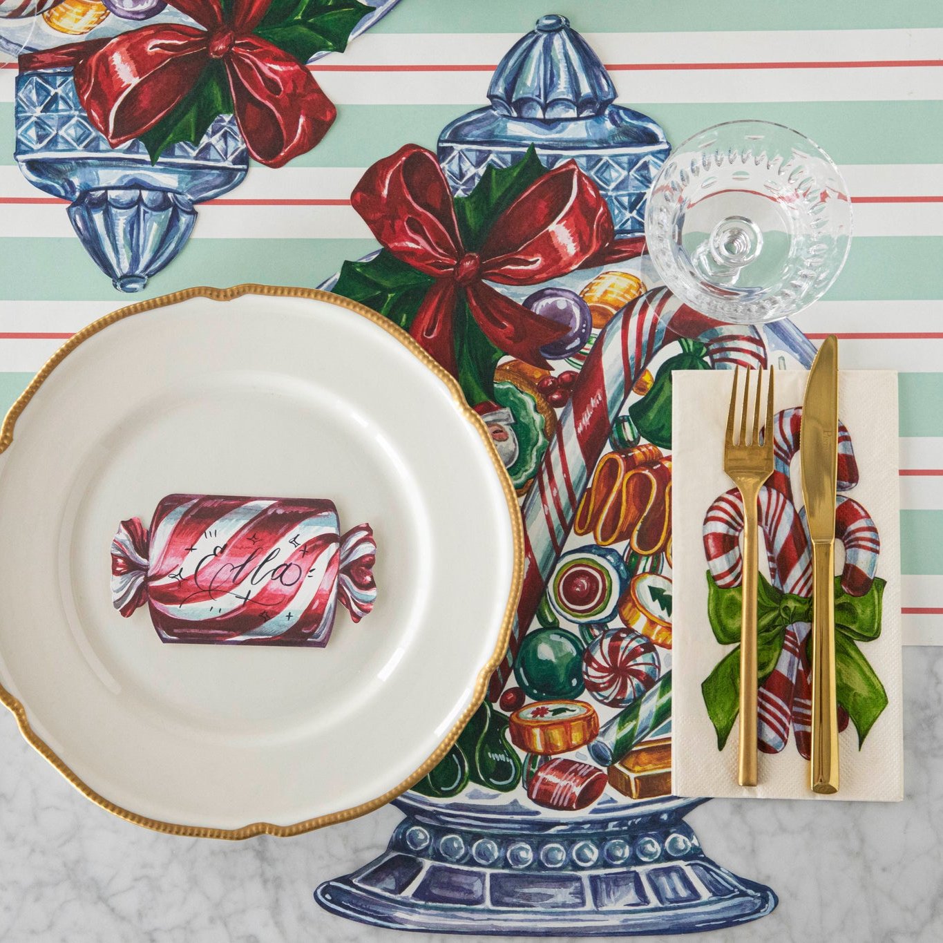 A table setting with the Die-cut Candy Jar Placemat on the Seafoam &amp; Red Awning Stripe Runner with the Christmas Candy Place Card resting on a gold-trimmed dinner plate.