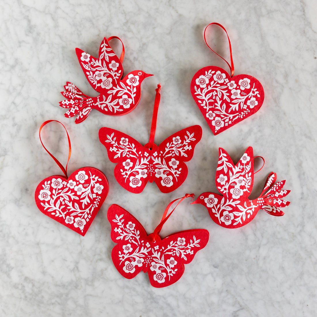 Red decorative ornaments with white floral patterns on a textured surface.