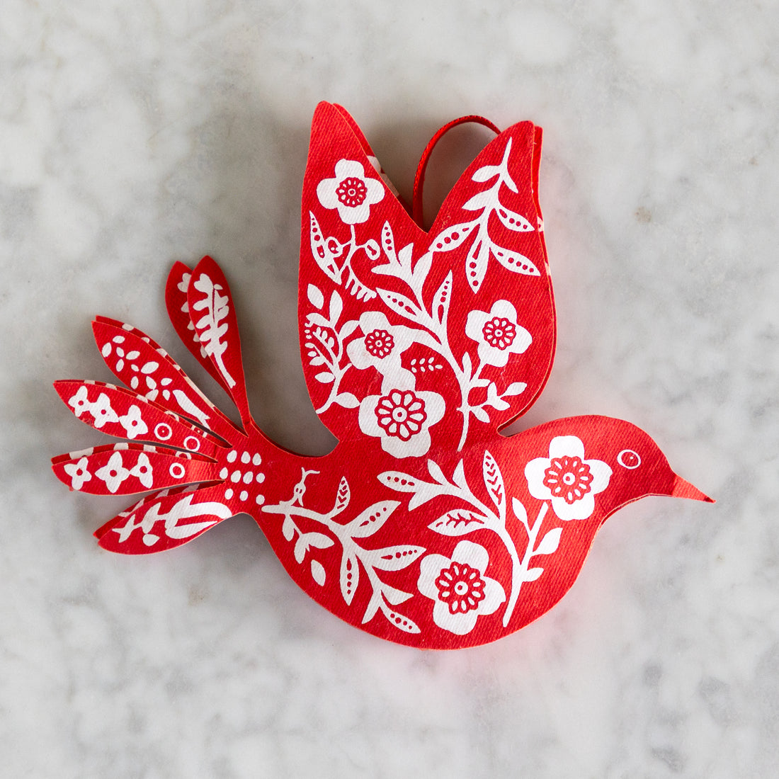 Red paper dove with white floral patterns on a light gray background.