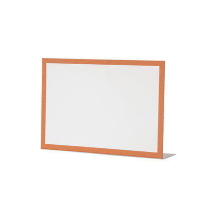 A free-standing, rectangular white table card with a simple orange frame around the edges.