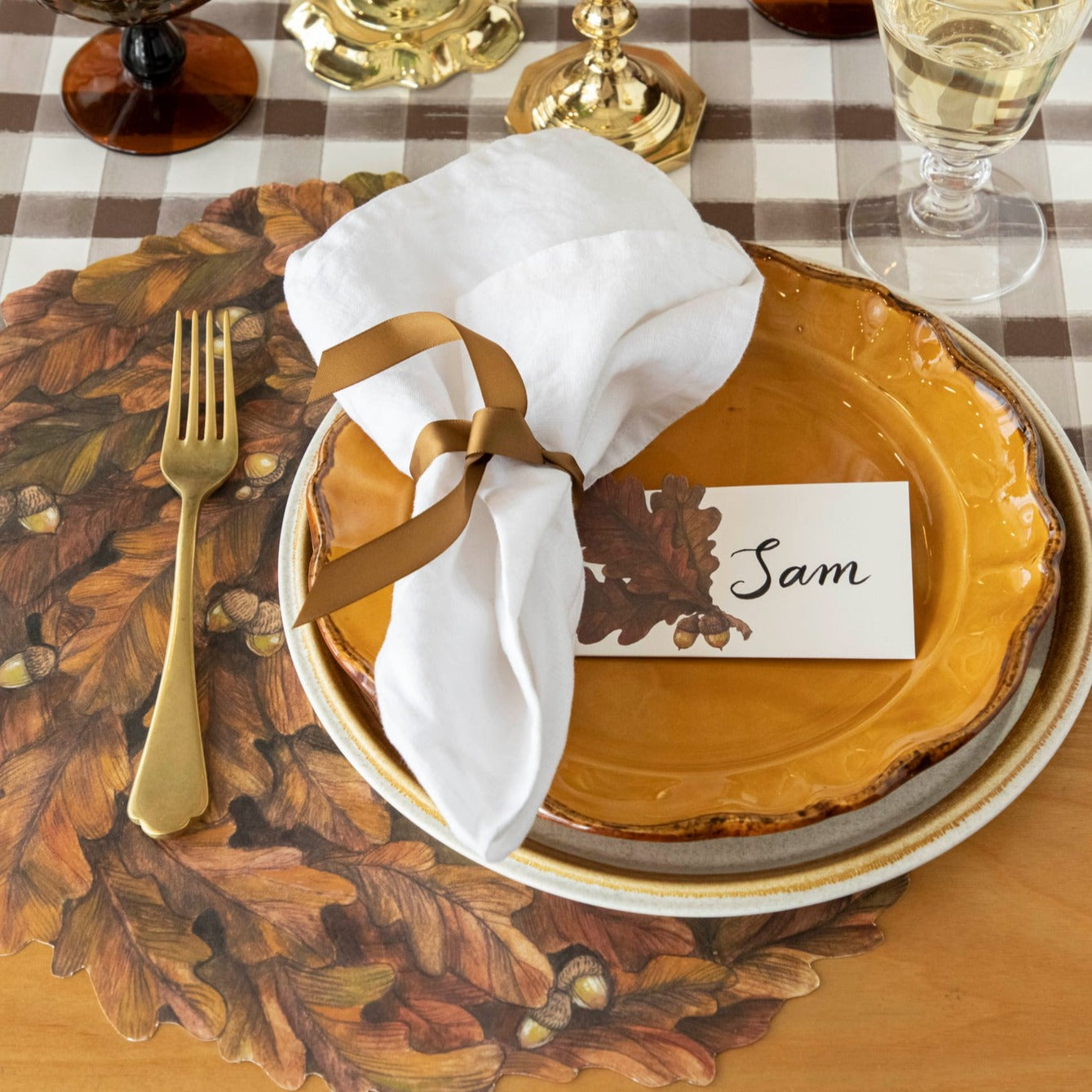 An elegant fall-themed place setting with a place card reading &quot;Sam&quot; laying flat on the plate.