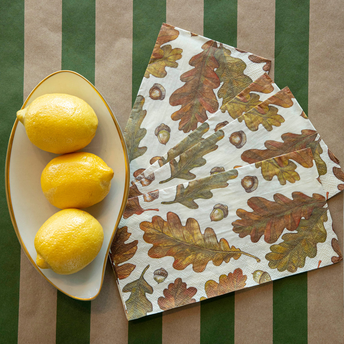 Four of the Autumn Leaves Guest Napkins fanned out on a table next to a bowl of lemons.