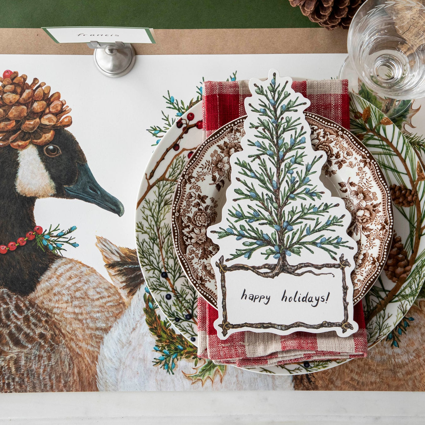 Christmas themed table setting featuring the Cedar Tree Table Accent atop vintage plates, Festive Geese Placemat and Kraft Green Classic Stripe Runner.