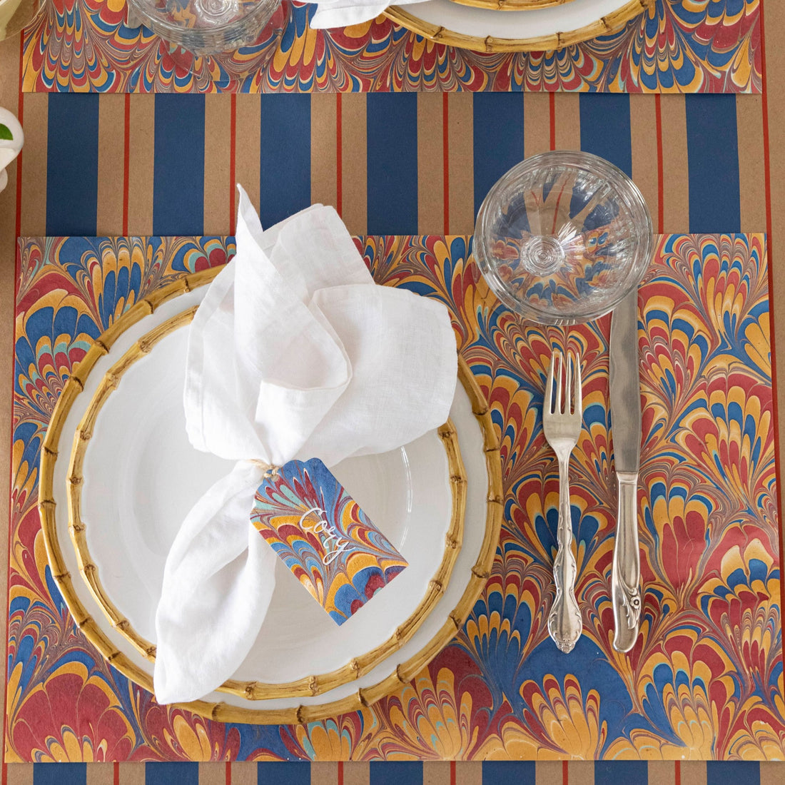 The Red &amp; Blue Peacock Marbled Placemat under an elegant place setting, from above.