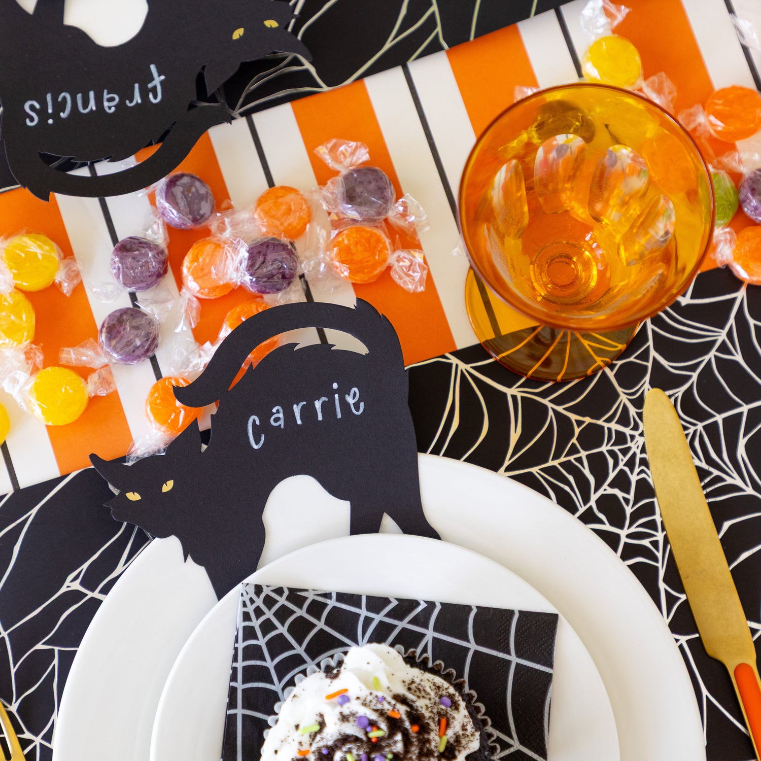 A Halloween place setting with the Black Cat Place Card reading "Carrie" in between the dinner and salad plate.