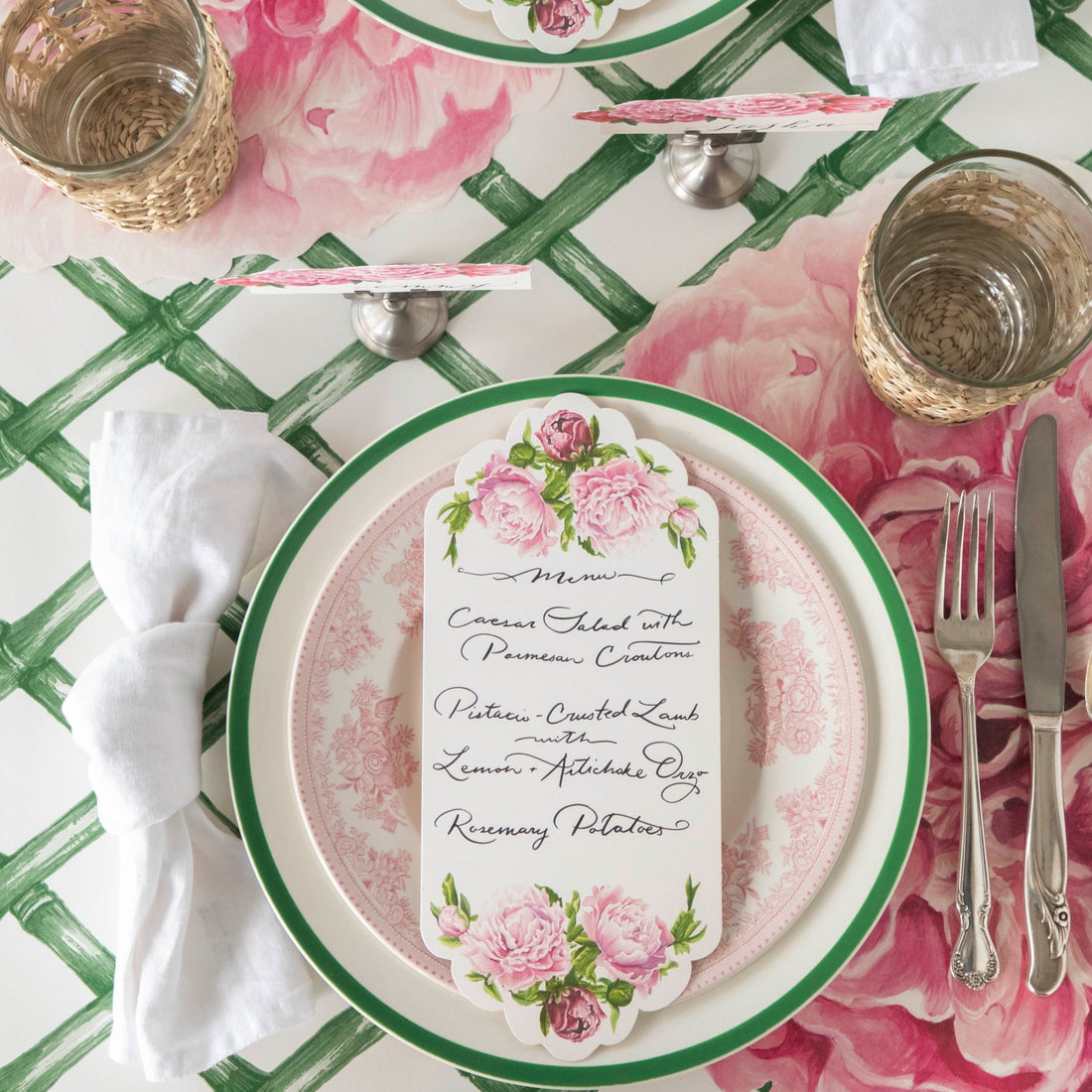Top-down view of an elegant floral place setting featuring a Peony Table Card with a menu written on it resting on the plate.