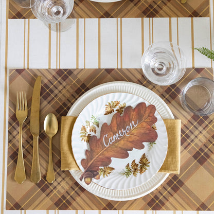A table setting with the Autumn Plaid Placemat with a plate and brass flatware, from above.