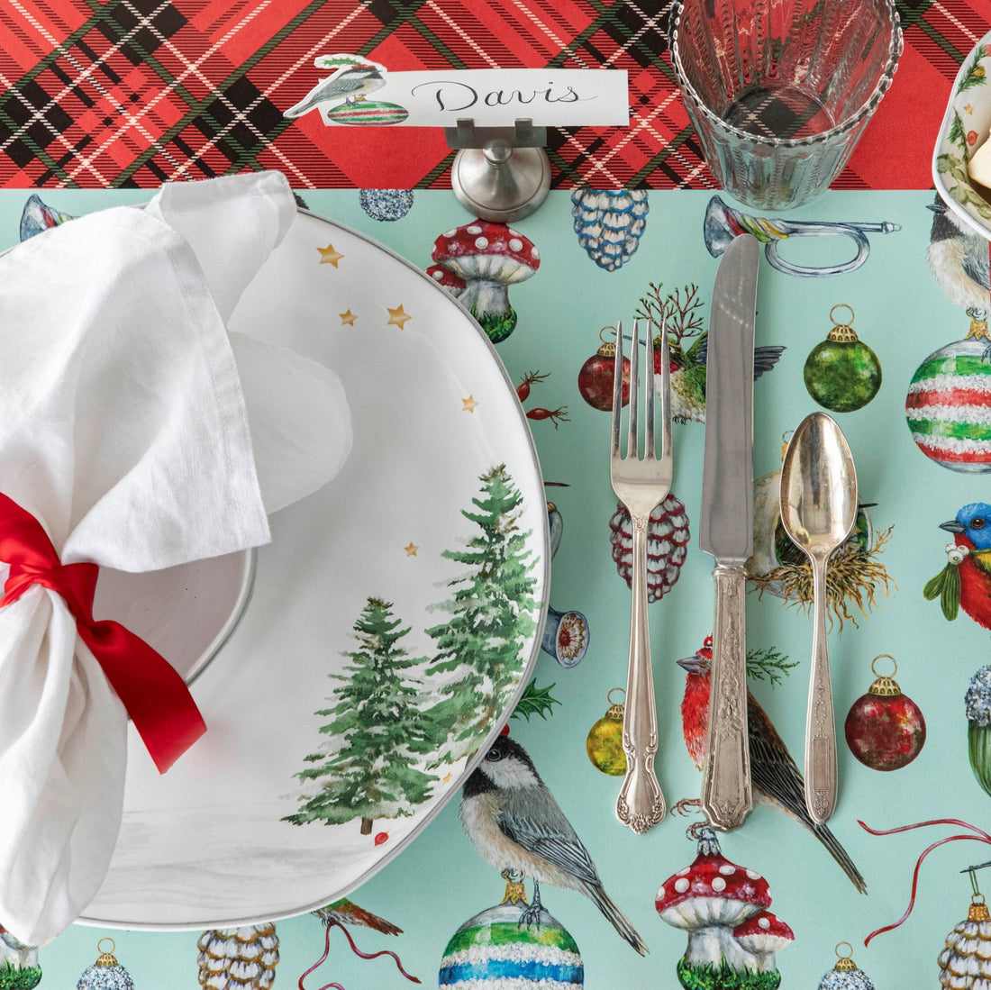 A Christmas themed table setting featuring the Baubles and Birds Placemat on the Red Plaid Runner.