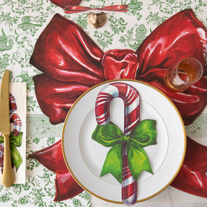 An elegant table setting featuring the Candy Cane Table Accent resting on a plate that sits on top of the Die-cut Christmas Bow Placemat.