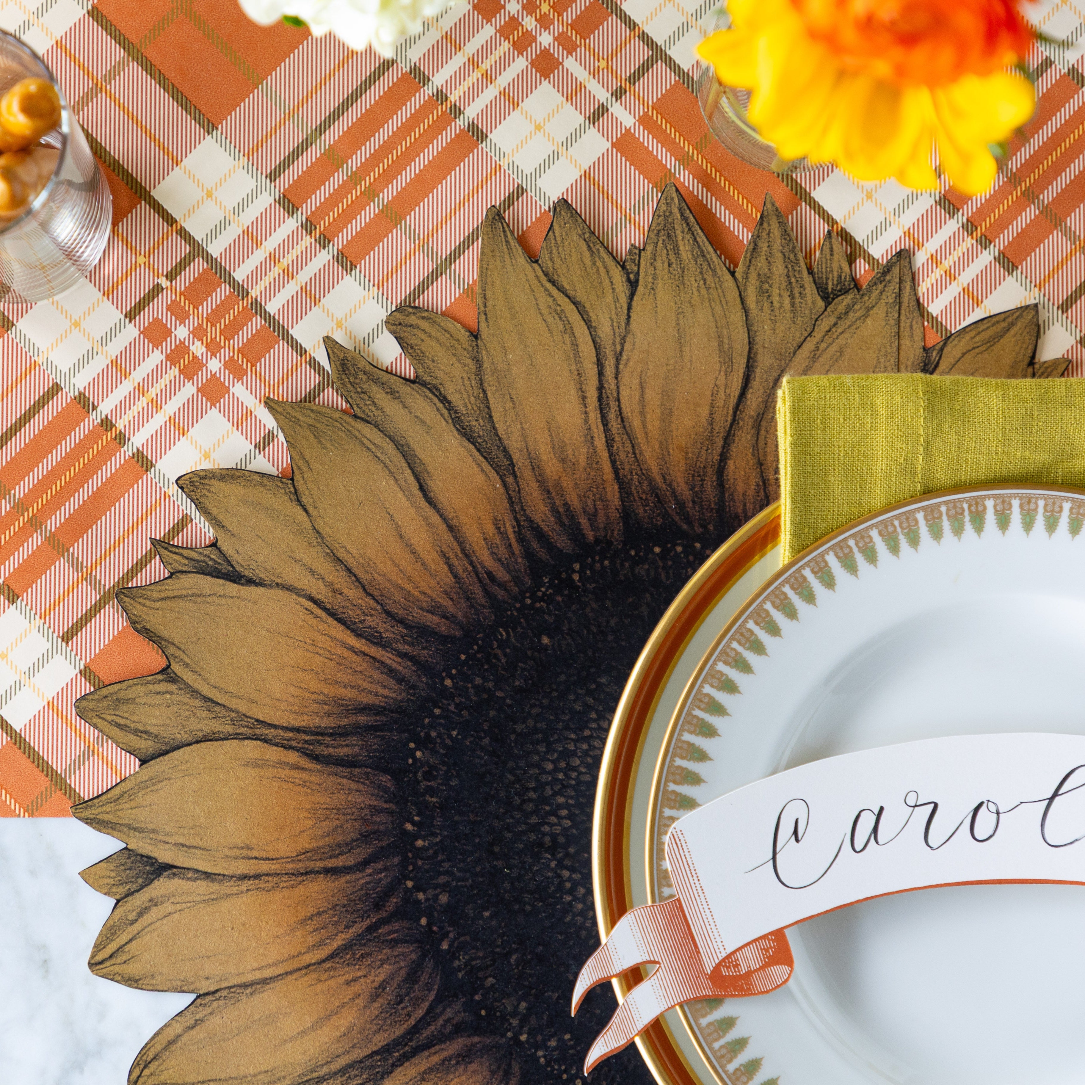 A place setting featuring the Die-cut Vintage Sunflower Placemat under vintage dinnerware, on the Orange Plaid Runner.