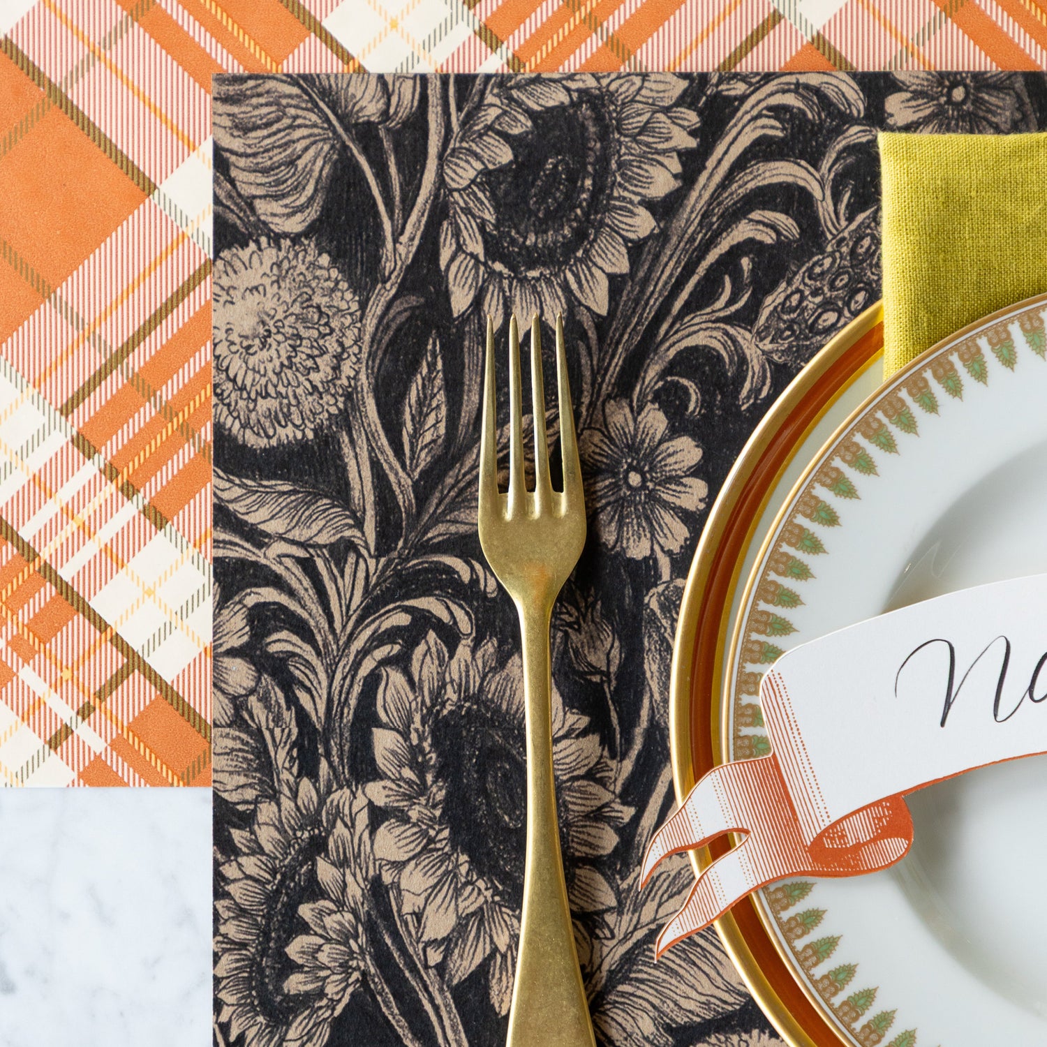 A place setting with the Sunflower Field Placemat under a gold fork, dinnerware, and Orange Plaid Runner underneath.