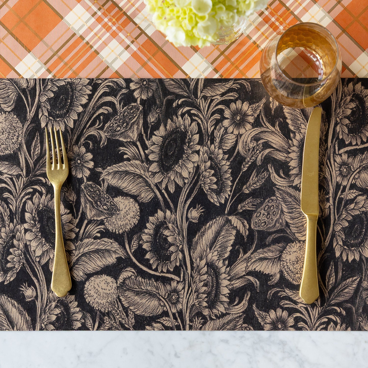 A place setting featuring the Sunflower Field Placemat under a wine glass, a gold fork and knife, and Orange Plaid Runner underneath.