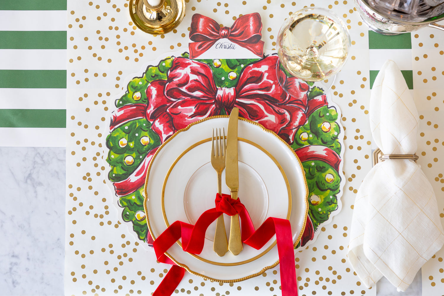 Festive place setting with the Holiday Wreath Placemat on the Confetti Runner with gold plates and cutlery laid out. 