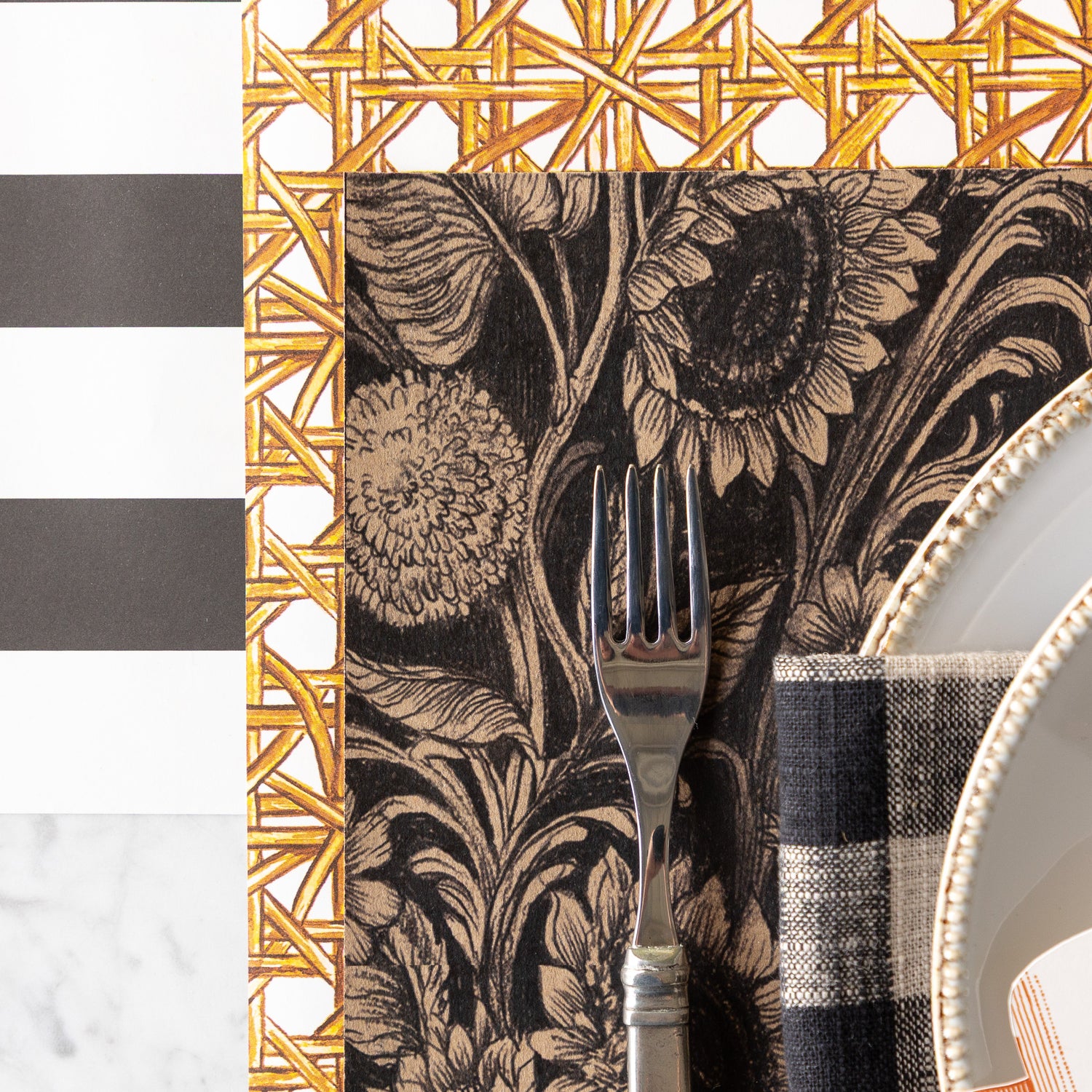 A place setting featuring the Sunflower Field Placemat on the Rattan Weave Runner rolled out vertically underneath, and Black Classic Stripe Runner rolled out horizontally under both.