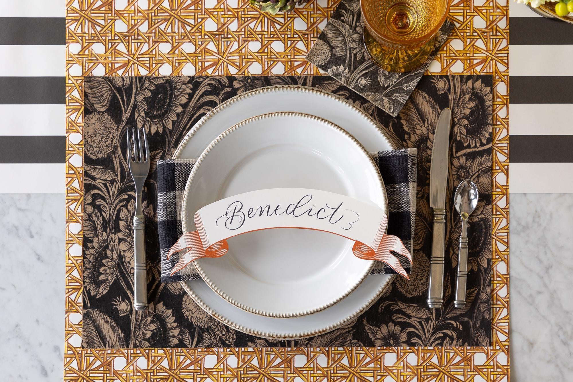 Elegant place setting with rattan lattice runner layered with a sunflower printed placemat and white plates.  