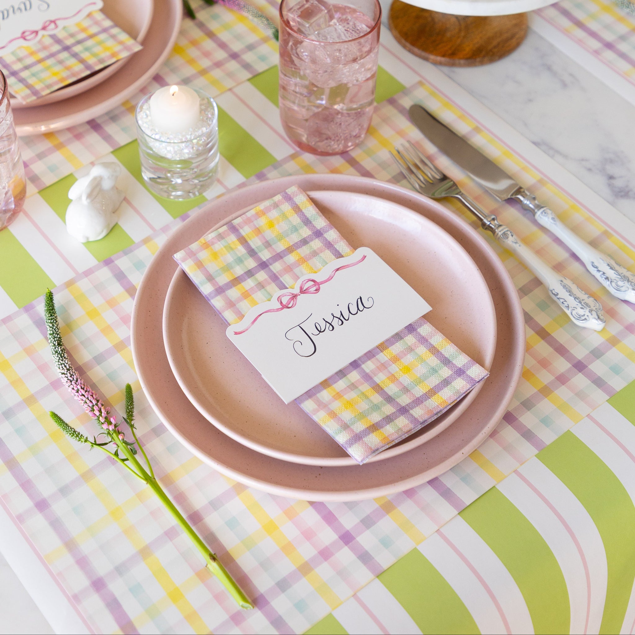 Dining table setting with pastel colors, including pink plates, Spring Plaid Placemat and Guest Napkin and Pink Bow Place Card on the Green &amp; Pink Awning Stripe runner.