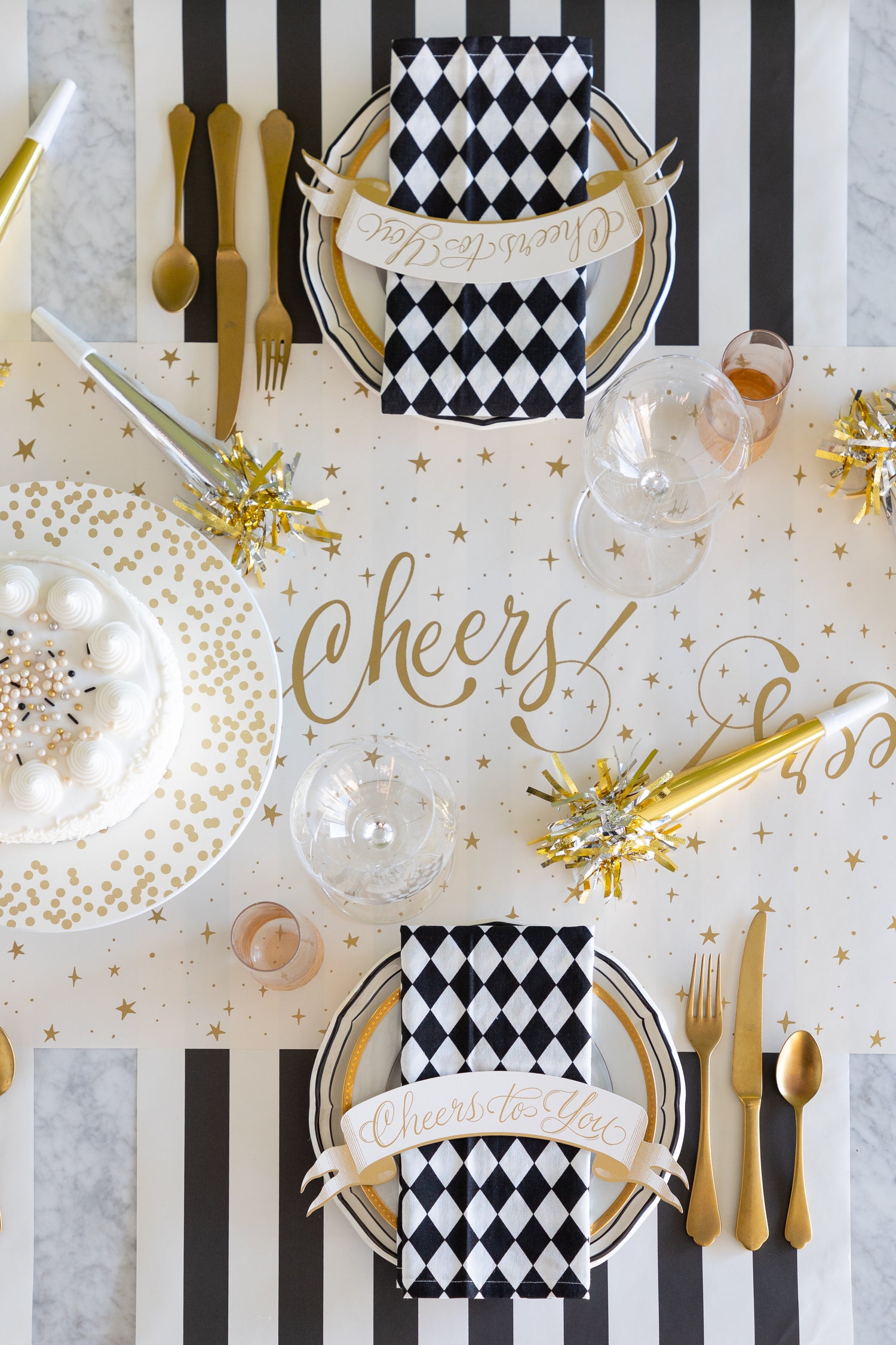 Decorative table setting with black and white checkered napkins, gold cutlery, and &