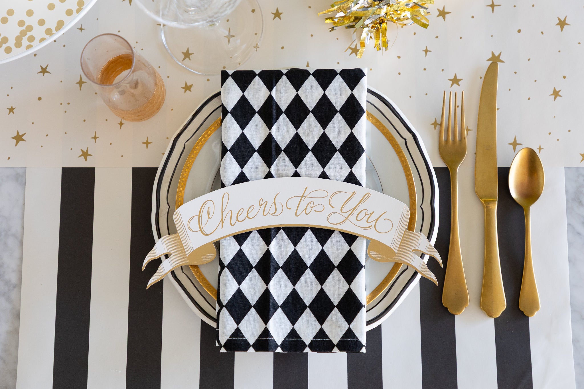 Decorative table setting with black and white checkered napkin, gold cutlery, and &