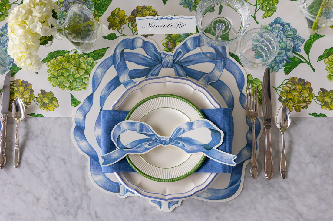 Table setting with Die-cut Heirloom Blue Bow Placemat, Cornflower Blue Icing on the Cake plates, Heirloom Blue Bow Table Accent and Place Card on the Hydrangea Table Runner.